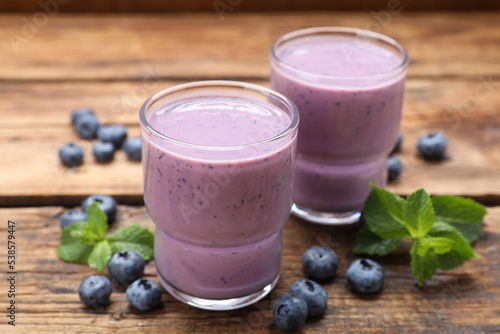 Glasses of blueberry smoothie with mint and fresh berries on wooden table