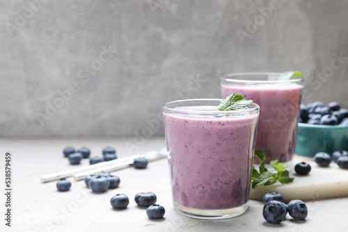 Freshly made blueberry smoothie on light grey table. Space for text