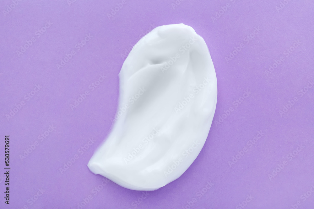 Sample of body cream on lilac background, top view