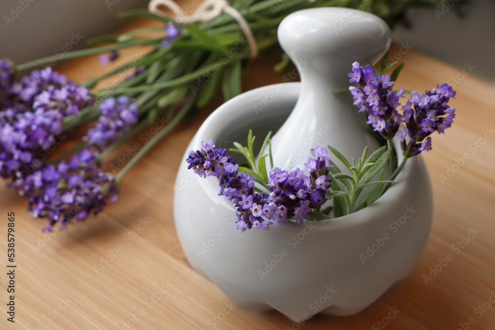 Mortar with fresh lavender flowers, rosemary and pestle on wooden table Mortar with fresh lavender flowers, rosemary and pestle on wooden table
