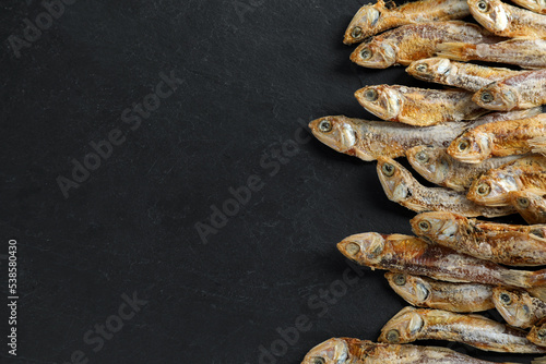 Delicious dried anchovies on black table, flat lay. Space for text