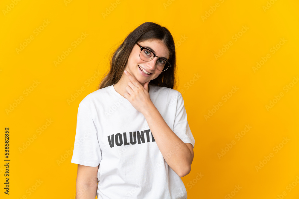 Young volunteer woman isolated on yellow background happy and smiling Young volunteer woman isolated on yellow background happy and smiling