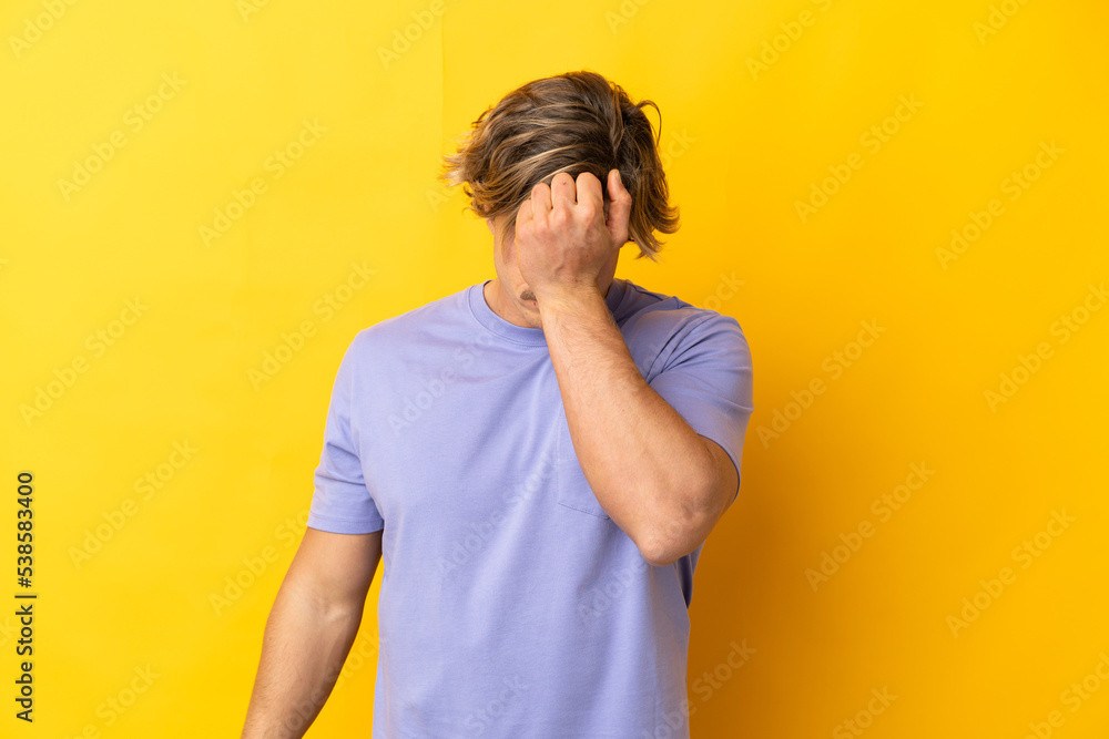 Handsome blonde man isolated on yellow background with headache Handsome blonde man isolated on yellow background with headache