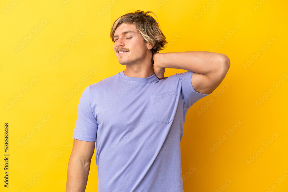 Handsome blonde man isolated on yellow background with neckache Handsome blonde man isolated on yellow background with neckache