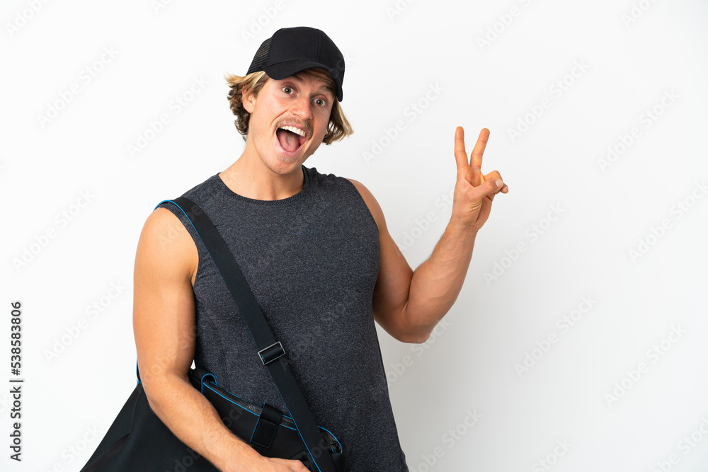 Young sport man with sport bag isolated on white background smiling and showing victory sign Young sport man with sport bag isolated on white background smiling and showing victory sign