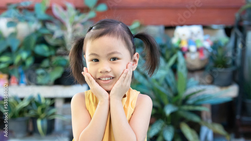 Positive charming 4 years old cute baby Asian girl, little preschooler child with adorable pigtails hair smiling looking at camera
