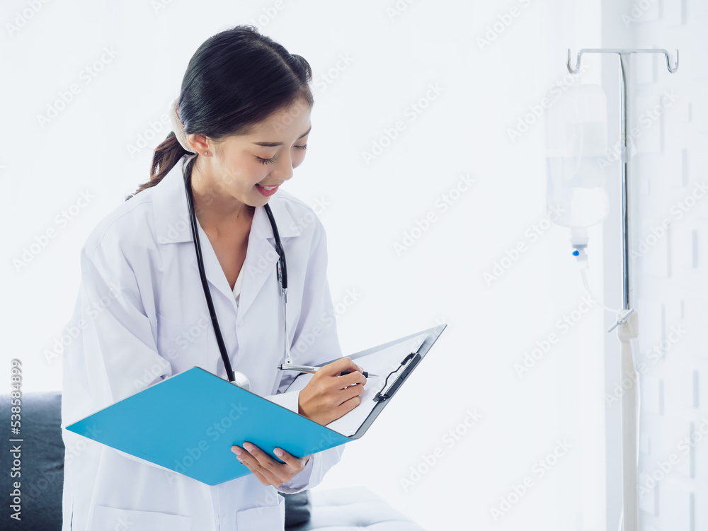Doctor with paper file. Asian female doctors writing up medical document or patient examination notes by pen on clipboard. Physician in white suit with stethoscope working in hospital or clinic. Doctor with paper file. Asian female doctors writing up medical document or patient examination notes by pen on clipboard. Physician in white suit with stethoscope working in hospital or clinic.