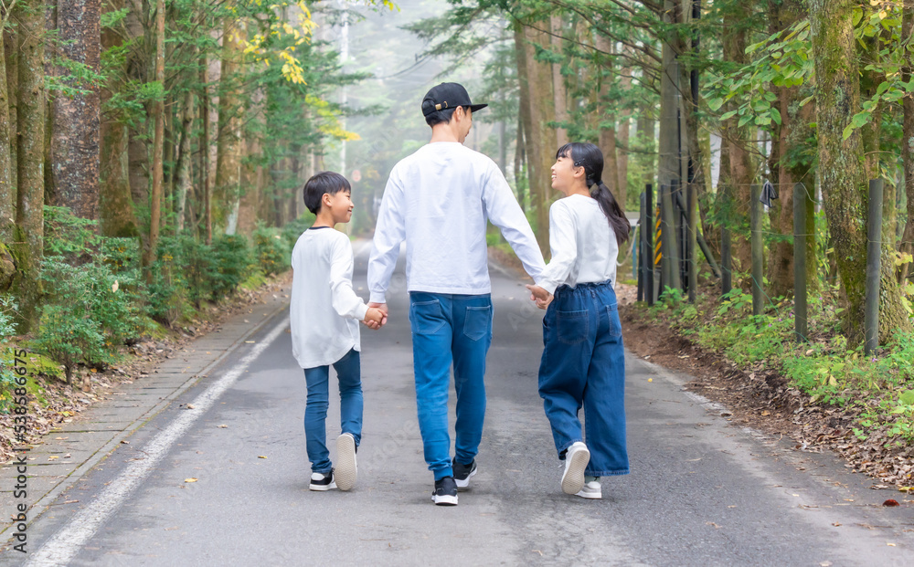 Obraz premium 手をつないで歩いている親子コーデの3人家族