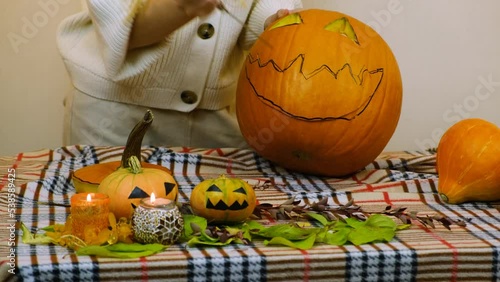 Medium plan. The girl cuts the mouth of a pumpkin. The girl prepares a pumpkin for Halloween. 4K.