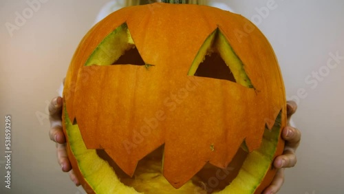 Close-up. Halloween. The girl is holding a pumpkin in her hands. The girl moves the pumpkin to the camera. 4k.