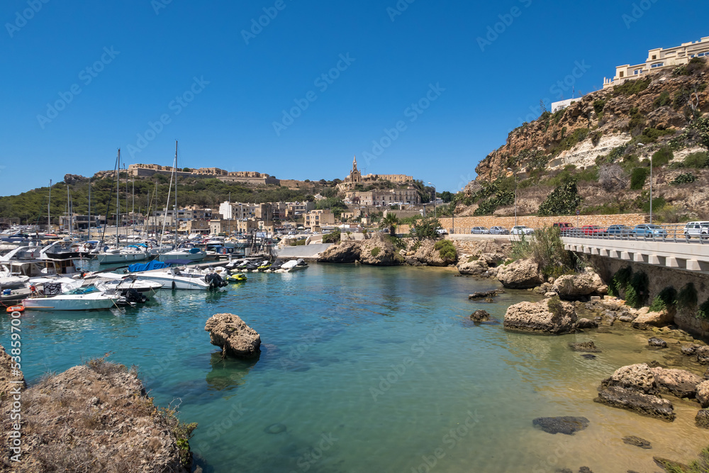 Beautiful shoreline on Gozo, Malta with boats anchored. Summer weather with clear blue sky.