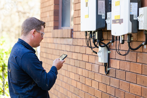 Electrician using mobile phone device to troubleshoot photo