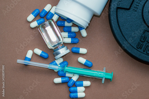 dumbbells, syringe with needle and vial with steroids. illegal doping in sport concept
