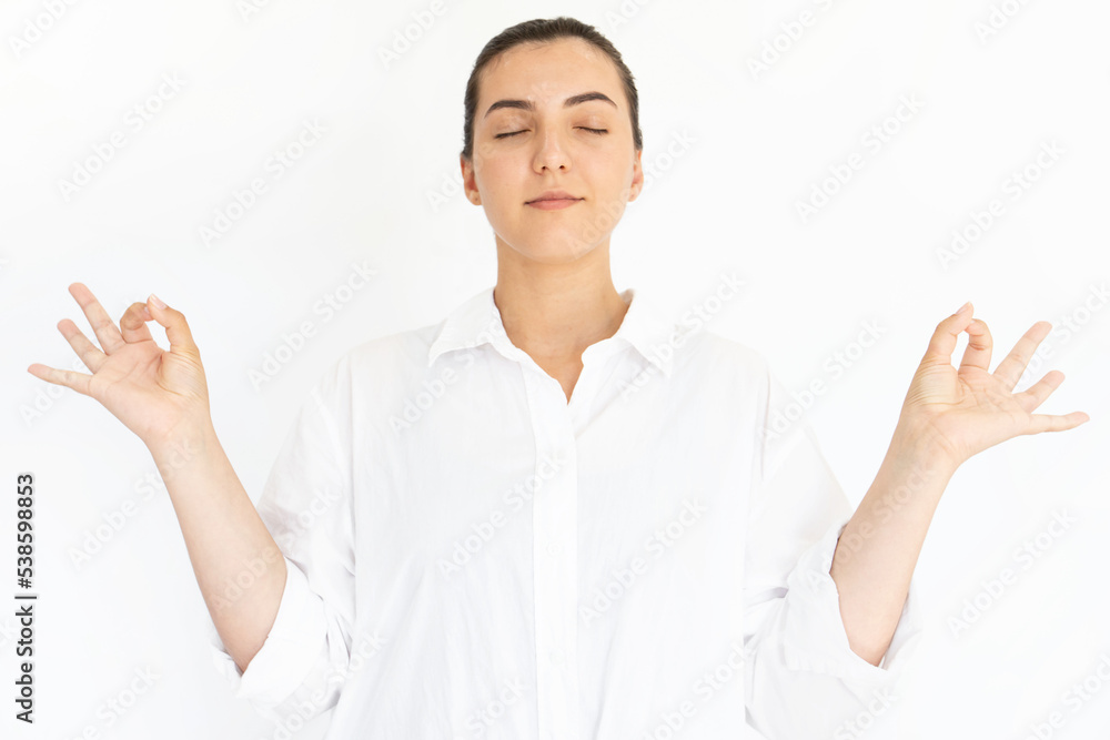 Portrait of calm young woman meditating with closed eyes. Caucasian lady wearing white T-shirt doing relaxation exercise against white background. Meditation, self-control, harmony concept Portrait of calm young woman meditating with closed eyes. Caucasian lady wearing white T-shirt doing relaxation exercise against white background. Meditation, self-control, harmony concept