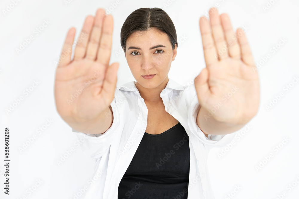 Portrait of serious young woman making refusal gesture. Caucasian lady wearing black top and white T-shirt looking at camera showing palms against white background. Refusal and forbiddance concept Portrait of serious young woman making refusal gesture. Caucasian lady wearing black top and white T-shirt looking at camera showing palms against white background. Refusal and forbiddance concept