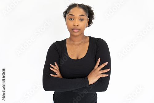Portrait of serious young woman standing with folded arms. African American lady wearing black longsleeve posing against white background. Confidence concept