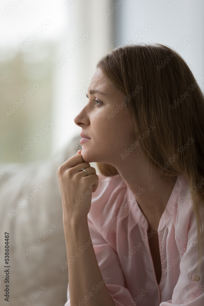 Frustrated depressed woman sit on sofa at home, looks into distance, worrying, feels anxious, lost in sad thoughts, thinks of personal life or relationships problems. Break up, divorce, close up shot Frustrated depressed woman sit on sofa at home, looks into distance, worrying, feels anxious, lost in sad thoughts, thinks of personal life or relationships problems. Break up, divorce, close up shot