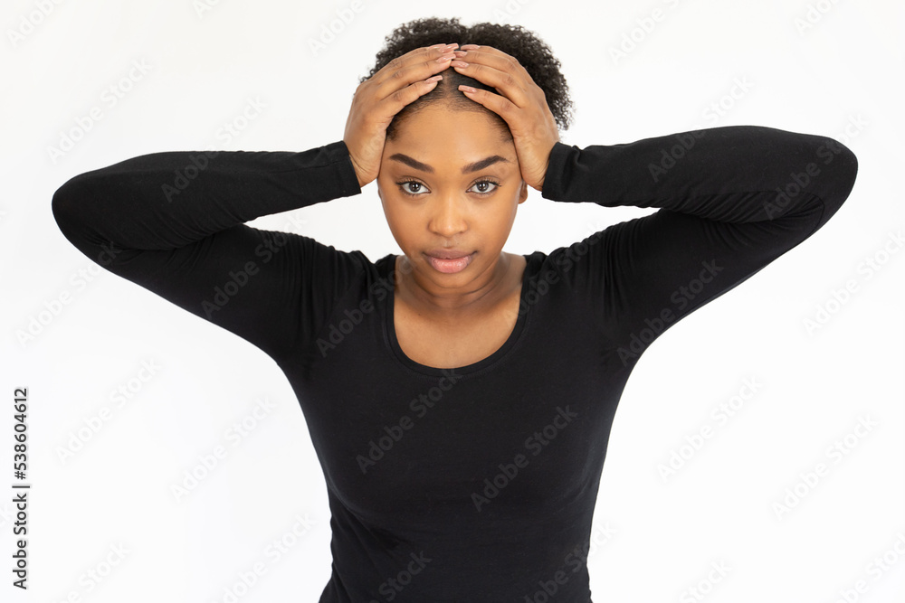 Portrait of worried young woman looking at camera. Upset African American lady wearing black longsleeve holding head in hands against white background. Stress and problem concept Portrait of worried young woman looking at camera. Upset African American lady wearing black longsleeve holding head in hands against white background. Stress and problem concept