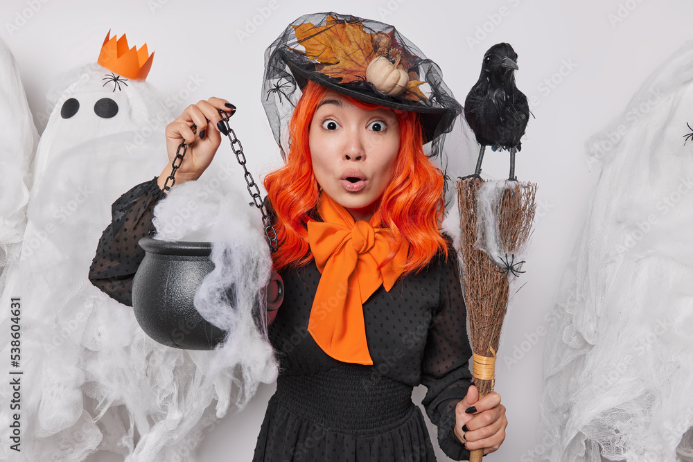 Shocked impressed woman pretends being witch holds caulderon broom and