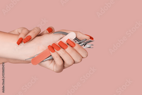Female hand with red nail design. Mate red nail polish manicure. Female model hand hold manicure tools.