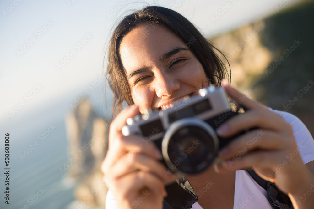 Close-up of smiling teen girl holding camera. Portrait of happy young photographer outdoors. Travel and photographing concept