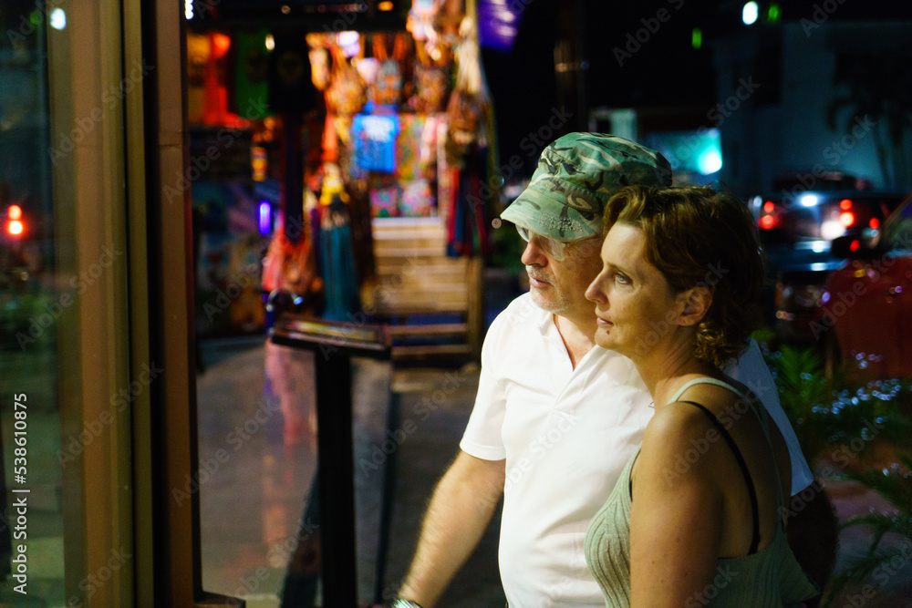 Adult couple window shopping at night in a city in Costa Rica Adult couple window shopping at night in a city in Costa Rica