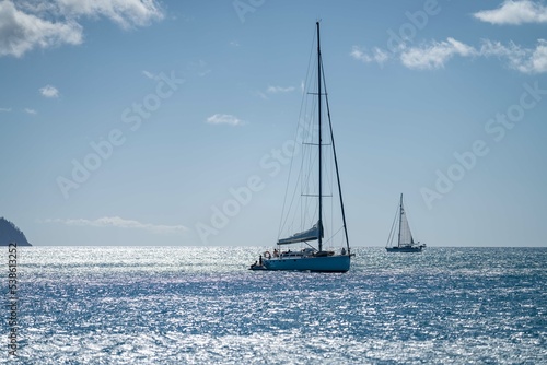 tourists walking on the beach in the whitsundays queensland, australia. travellers on the great barrier reef, over coral and fish. tourism yachts of young people partying on the water