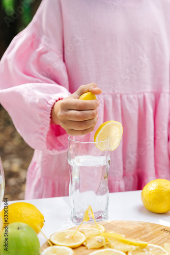 a girl in a pink dress makes lemonade from a fresh lemon