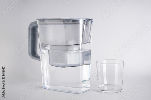 Water filter jug and a glass of water on a grey background. Close-up.