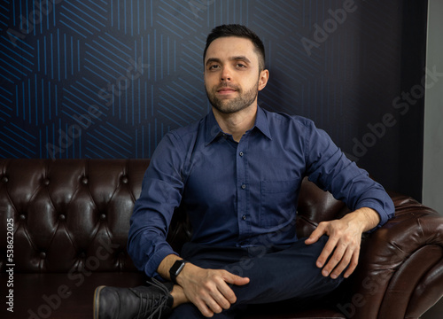 portrait man sitting on a sofa, man in business shirt in his office, young businessman in his living room