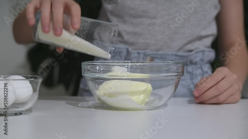 A girl of Caucasian appearance prepares a culinary product, pours sugar into the dough.