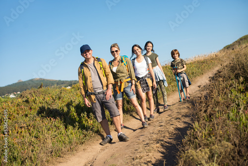 Hiking family of five posing and smiling outdoors. Portrait of parents with teen daughters and son trekking in countryside. Active family weekend concept