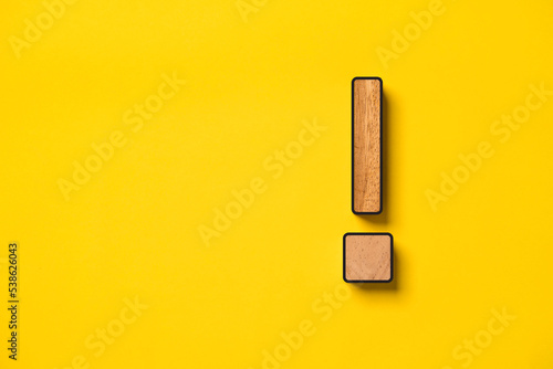 Wooden caution warning sign on yellow background for danger notification , error maintenance and exclamation concept.