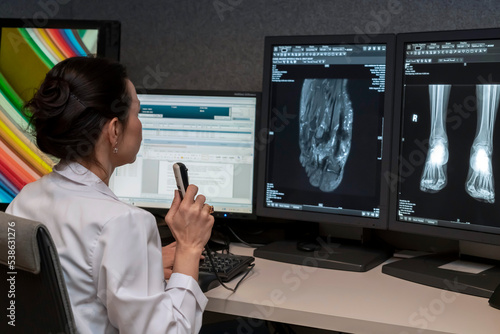 Billede på lærred radiology doctor examines foot, ankle x-ray, mr image and reports with microphone looking computer screen, X-ray analysis room reading X-rays of a heel, toe and other parts of the body