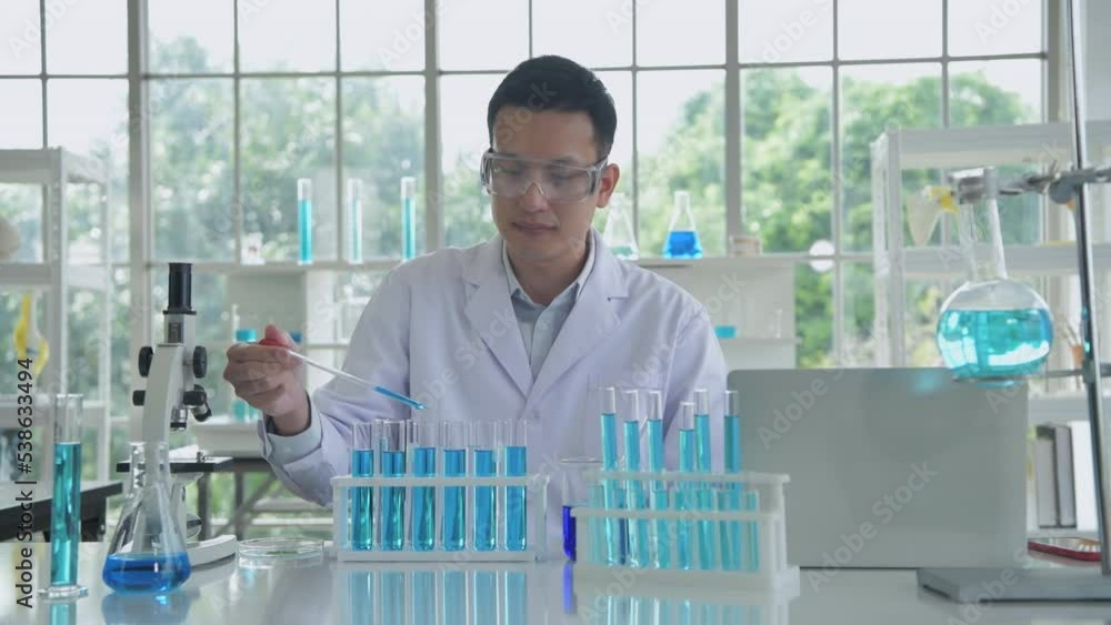 Research concept of 4k resolution. An Asian man dripping liquid into a test tube. Research concept of 4k resolution. An Asian man dripping liquid into a test tube.