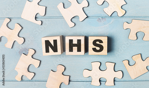 Blank puzzles and wooden cubes with the text NHS lie on a light blue background.