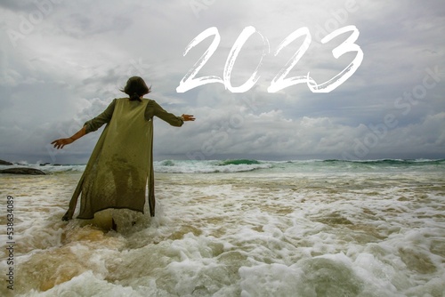 Woman walking in the sea towards the new year 2023 full of hope for the new year, new year 2023 full of freedom and dream, woman attracted by the sky, happy new year 2023, 2023 miracle
