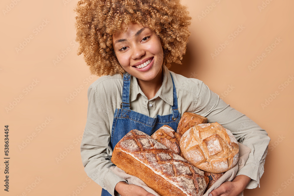 Happy young woman works in small bakery carries fresh aromatic bread