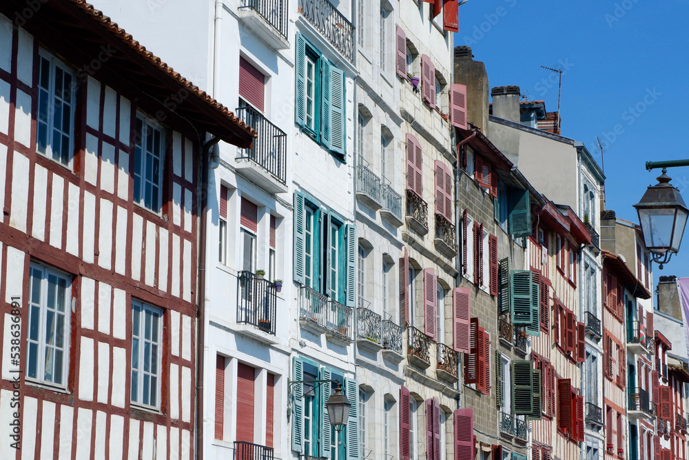 Colourful vintage facades of typical french basque homes with shutters and windows of faded colours downtown in Bayonne, Basque country, Spain