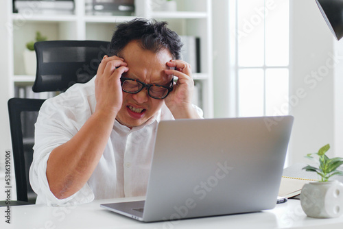 фотографія Middle-aged Asian man feel headache, symtom of stroke during working