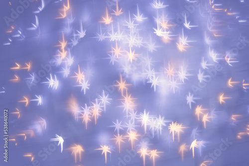 Christmas or New Year abstract magic lights background, sparkling white stars bokeh on blue purple fon as winter holiday backdrop. Xmas mood photo, blurred effect, celebration illumination