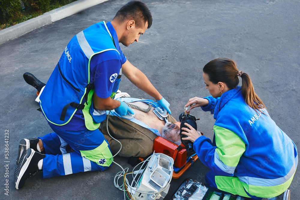 Team of paramedics performing CPR with mobile defibrillator and
