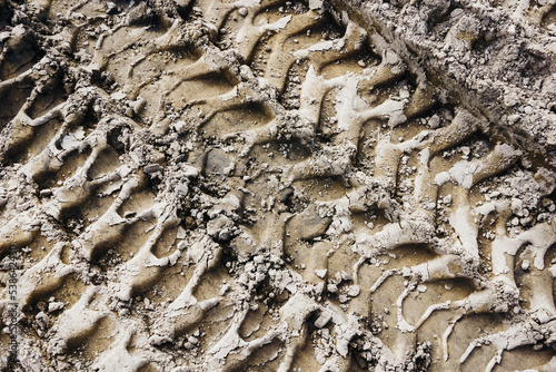 Fototapeta Naklejka Na Ścianę i Meble -  Tyre mark background. Tire track shape. Trail lines on dry brown sand pattern. Road construction site backdrop. Heavy machinery imprint. Dried mud vehicle wheel shape.
