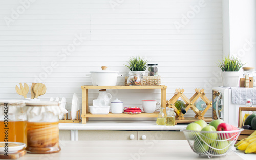 Interior design of cozy kitchen room at comfortable home in minimal style with wooden equipment of forks, spoons, pot and ingredients in wood and white colors. House Decoration and Renovation Concept.