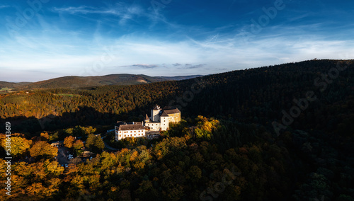 panorama of Lockenhaus Castle surrounded by autumn forest in warm evening light