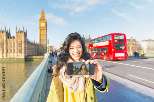 Photography Woman in London taking a selfie with Big Ben and red double decker bus on backgr