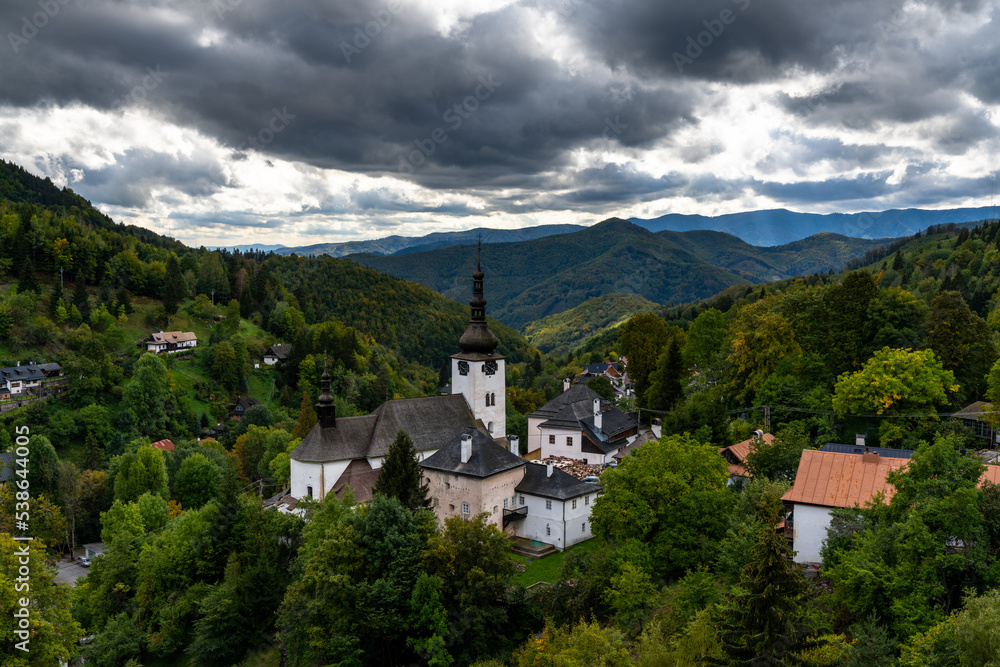 view of the village and Roman Catholic church in Spania Dolina with green summer forest