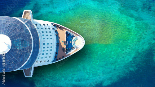 Aerial drone top down photo of latest technology cruise liner ship bow anchored in tropical exotic island bay with emerald sea