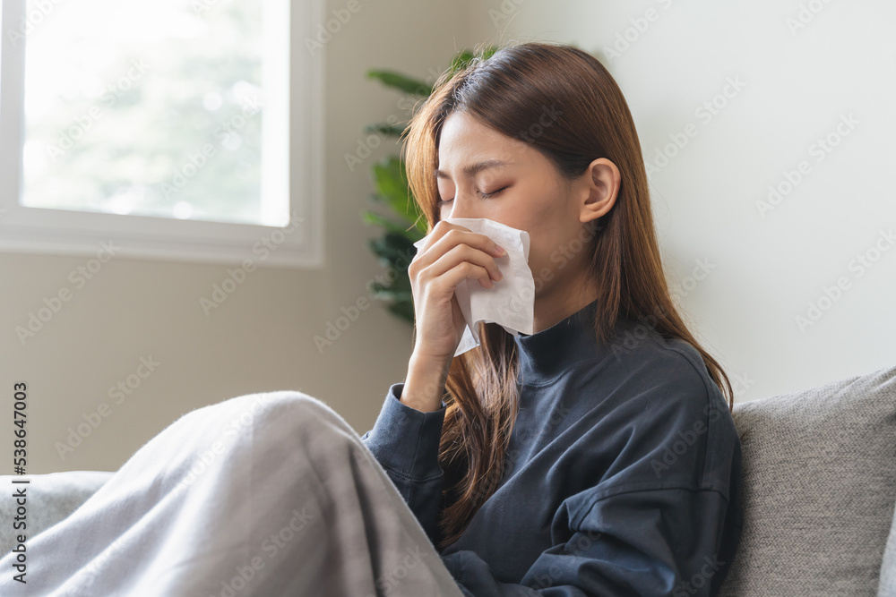 Sick at home concept. Woman sneezing on the sofa in winter season. Sick at home concept. Woman sneezing on the sofa in winter season.