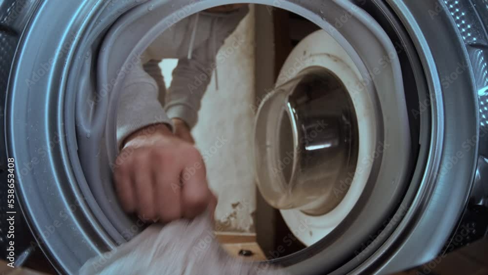 Young man sticks dirty towel into a laundry washing machine. view from inside. Young man sticks dirty towel into a laundry washing machine. view from inside.